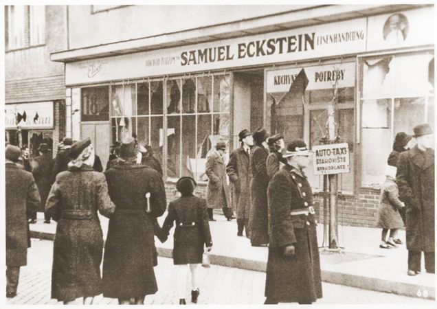 Pedestrians view the vandalized iron goods store owned by a Jew